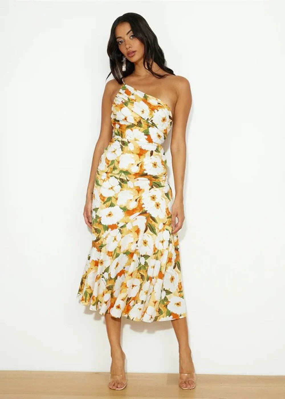 Full length shot of a woman wearing a one-shoulder floral midi dress with a ruffled hem.