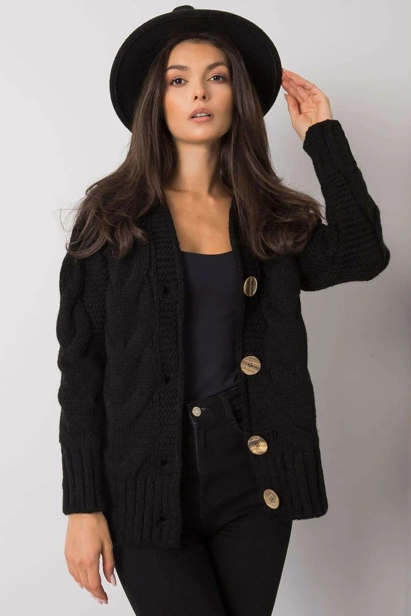 Black knit cardigan with cable knit details and large wooden buttons, worn by a model.