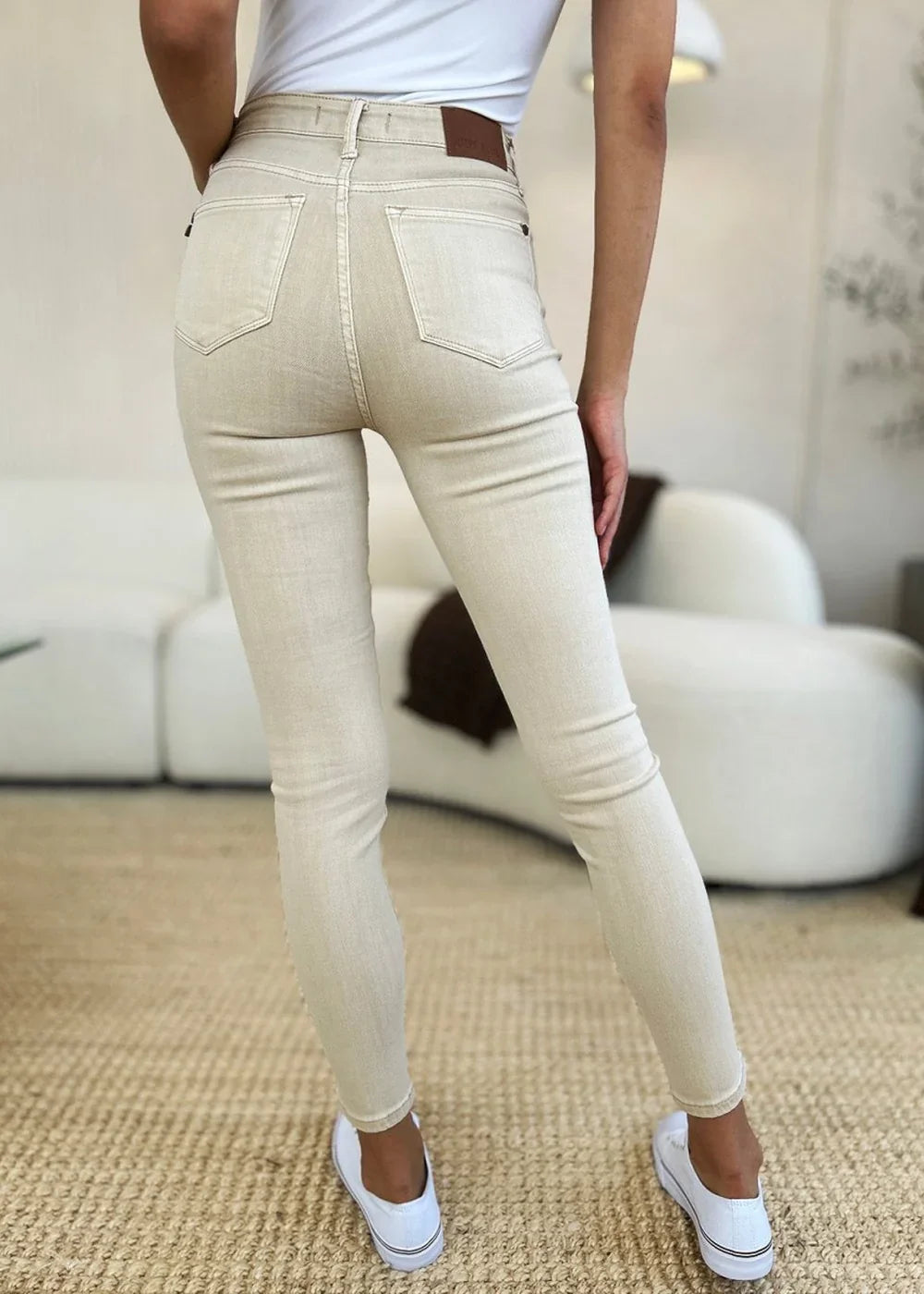 Light beige skinny jeans with a leather back tag, shown from the back on a model.
