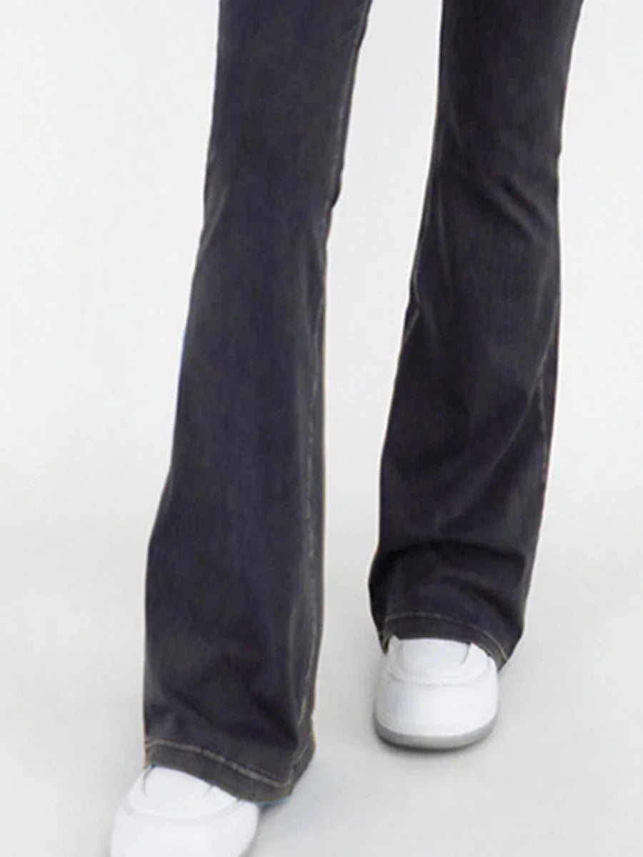 Close-up of dark wash flare jeans with white sneakers.