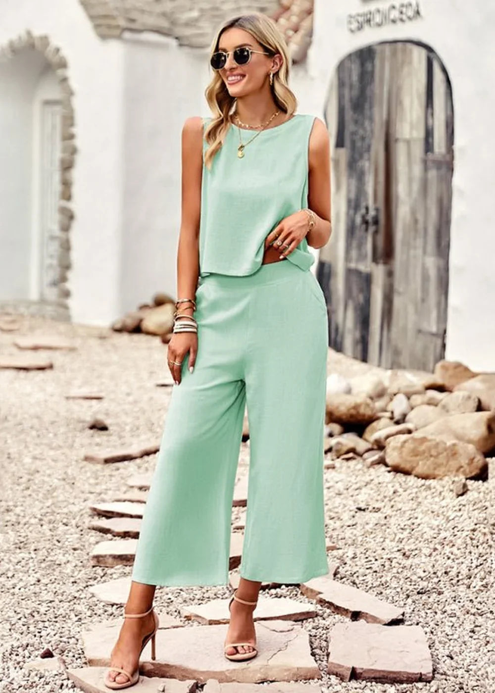 Woman in a mint green sleeveless crop top and wide-leg pants set, with strappy heels.