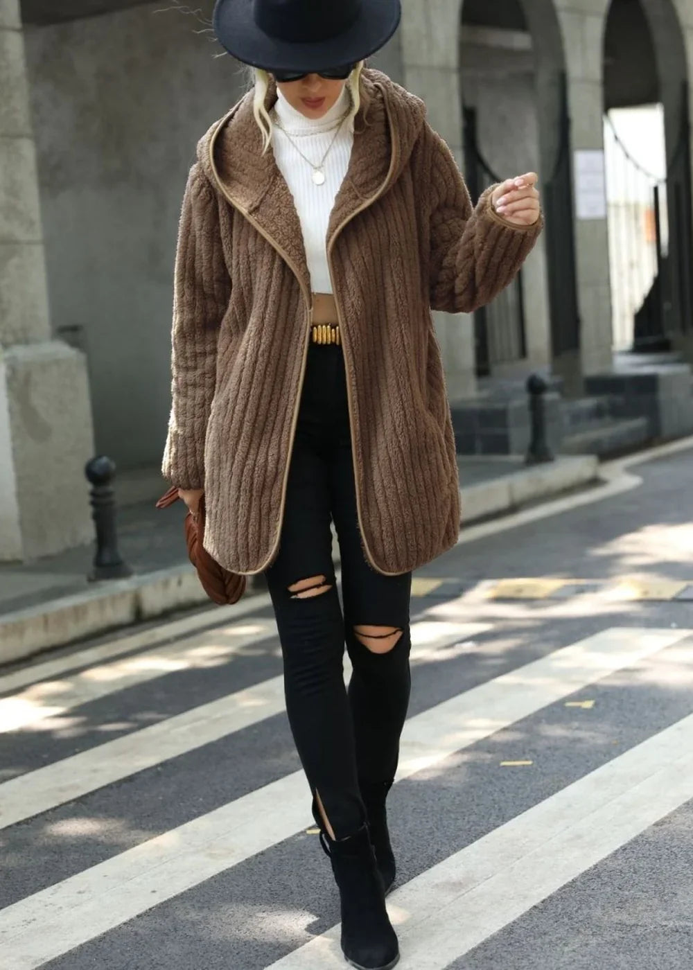 Brown fuzzy hooded jacket with ribbed texture and tan trim on model, styled with ripped black jeans.