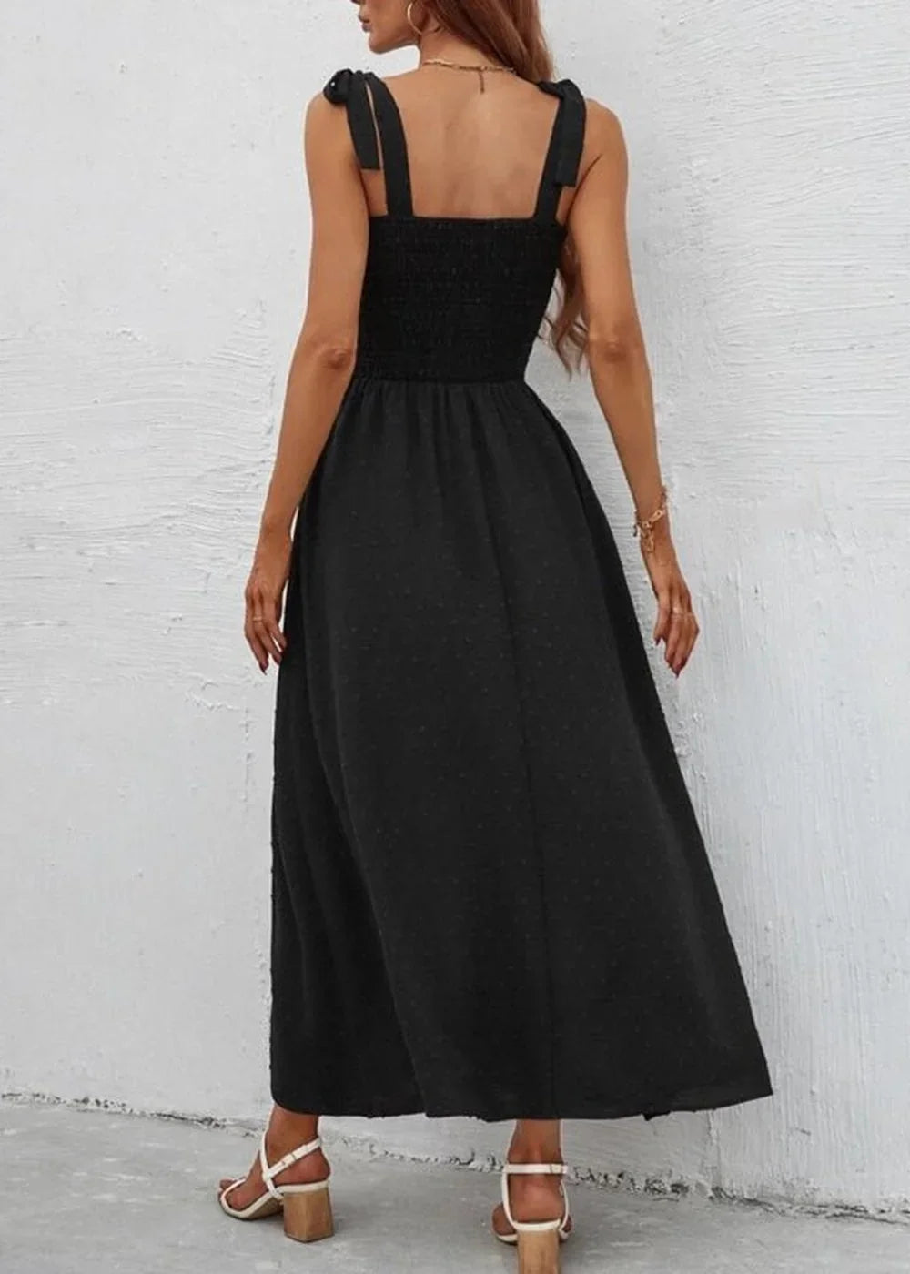 Black empire waist maxi dress with smocked bodice and tie shoulder straps, shown from the back on a model.