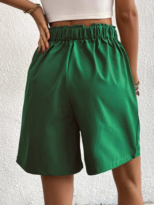 Emerald green polyester shorts with a ruffled elastic waistband and a regular fit.