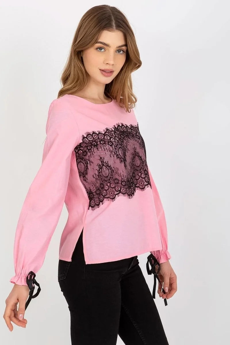 Pink long-sleeved top with black lace detail on the front, tie details on sleeves, and black pants.