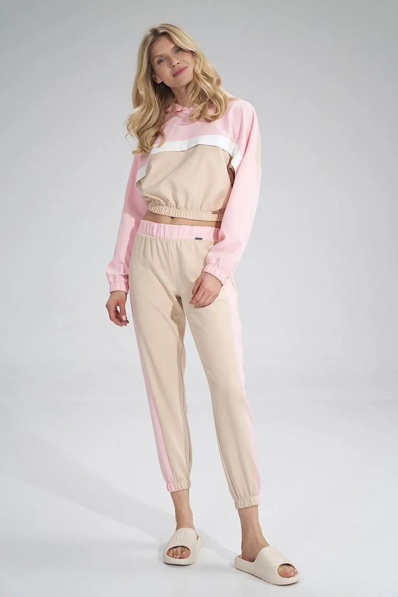 A woman in a pink and beige striped tracksuit with white accents and cream slides.