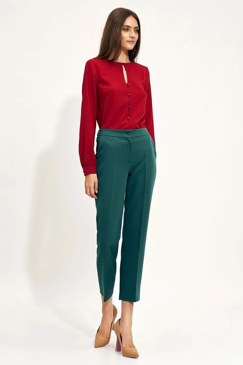 Full length shot of a woman wearing dark teal, high-waisted, straight-leg trousers with a single button closure.