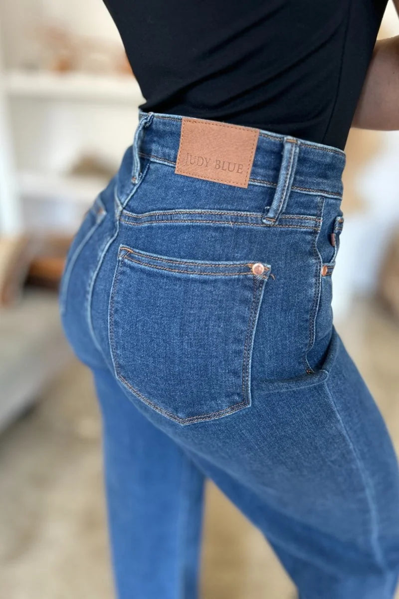 Close-up of dark wash denim jeans with a brown leather patch on the back pocket.