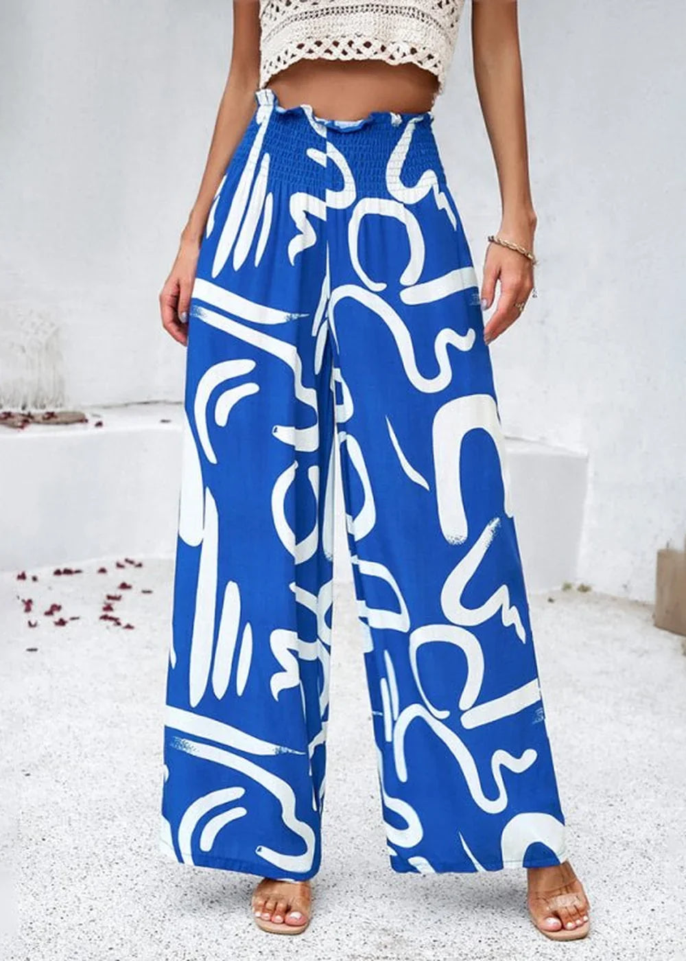 Vibrant blue wide-leg pants with a bold white abstract print and smocked waistband.