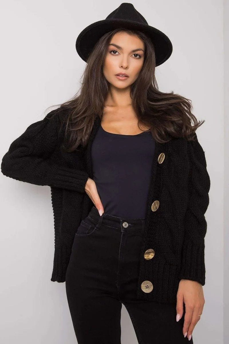 Black chunky knit cardigan with braided cable knit detail and large brass buttons, worn by a model.