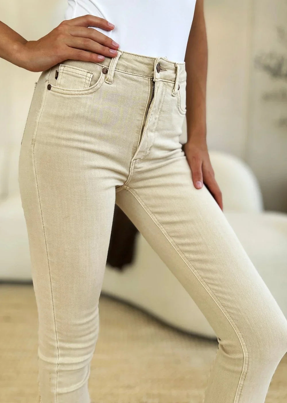 Close-up of bone-colored cotton blend jeans with a zipper fly and a regular fit on a model.