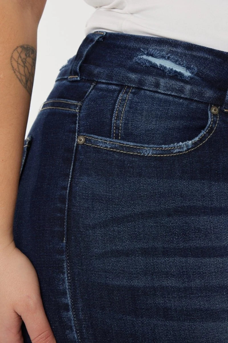 Close-up of dark wash distressed denim jeans with frayed pocket edges and a ripped detail at the waistband.