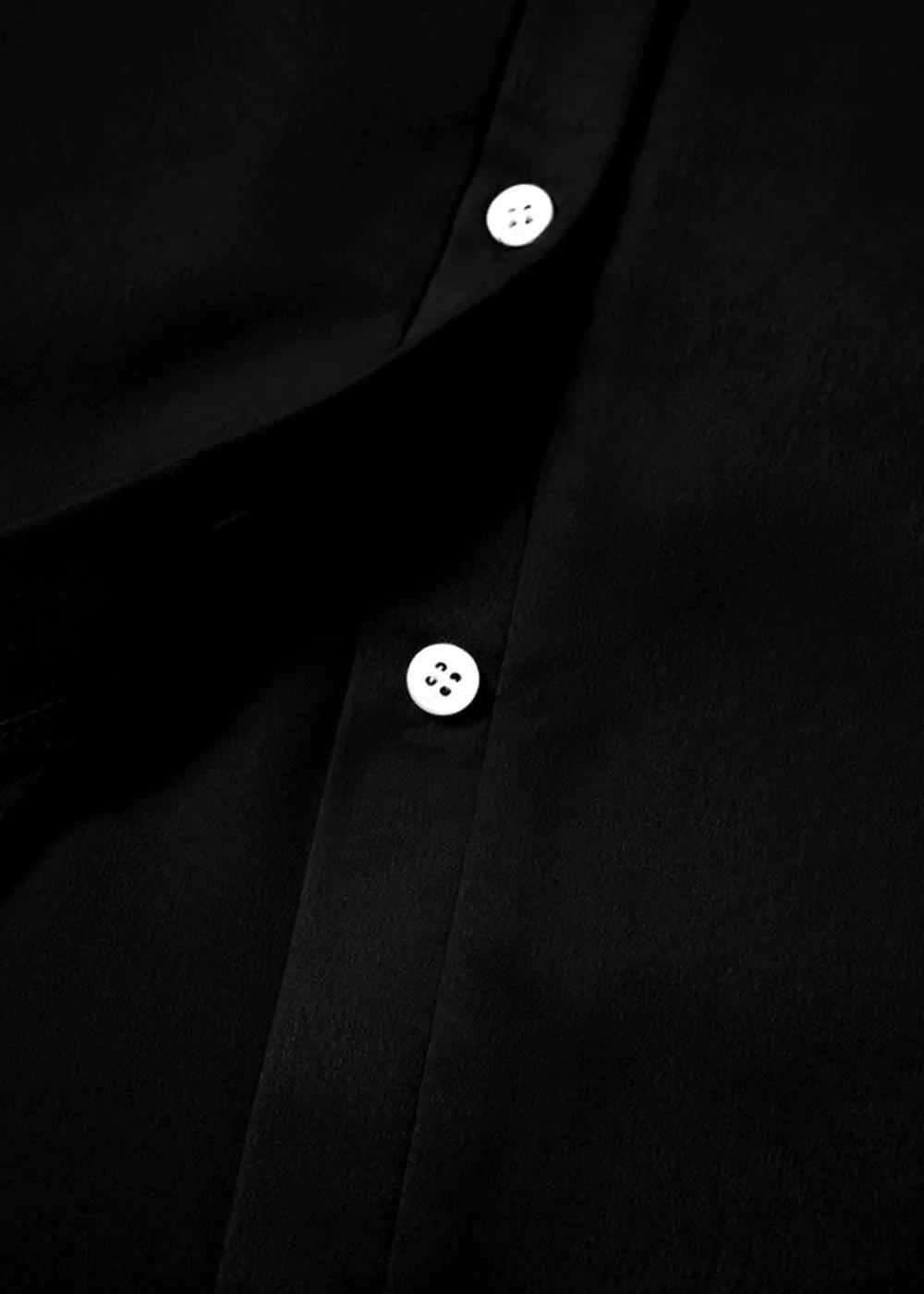 Close-up of a black polyester shirt with two white buttons.