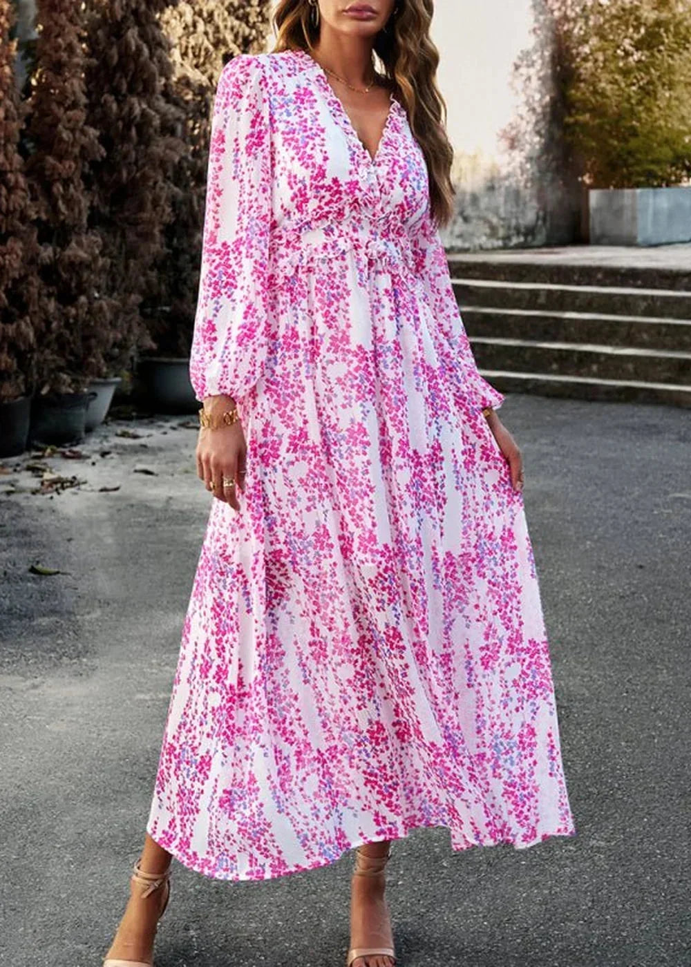 Flowy white maxi dress with a vibrant pink and blue floral pattern, featuring a V-neck and long sleeves.