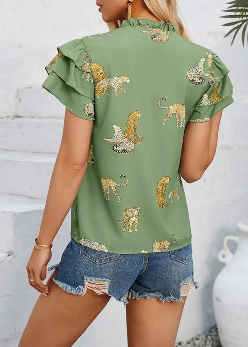 Green short-sleeve top with all-over leopard print and ruffled sleeves, worn by model.