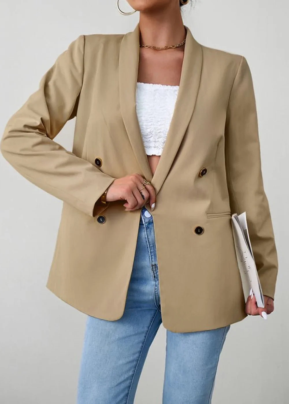 Tan double-breasted blazer with dark buttons over a white lace crop top and light wash jeans.