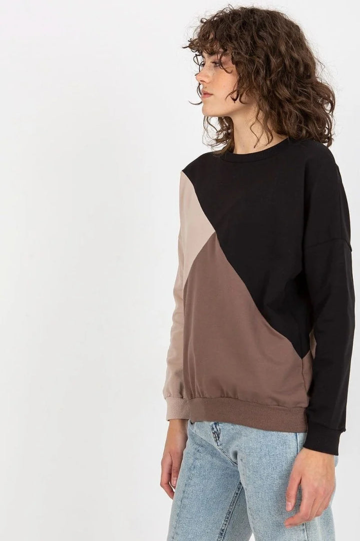 Woman in a color-blocked sweatshirt with black, beige, and brown panels.