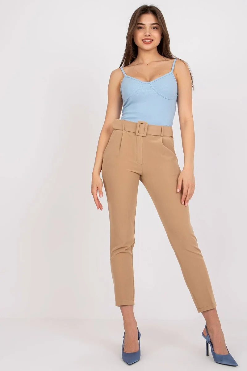 Tan high-waisted pants with a belt and a light blue camisole on a model.