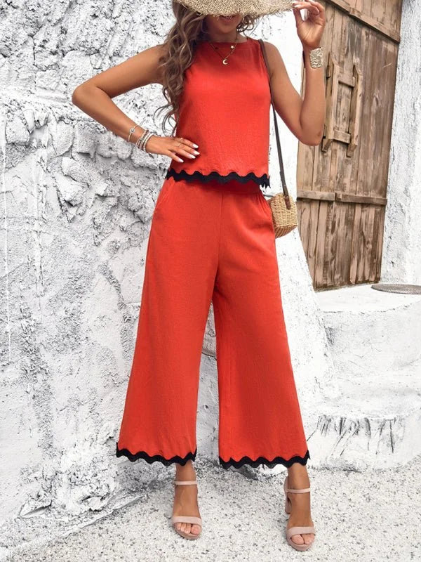 Orange wide-leg pant suit with black scalloped trim, on model.