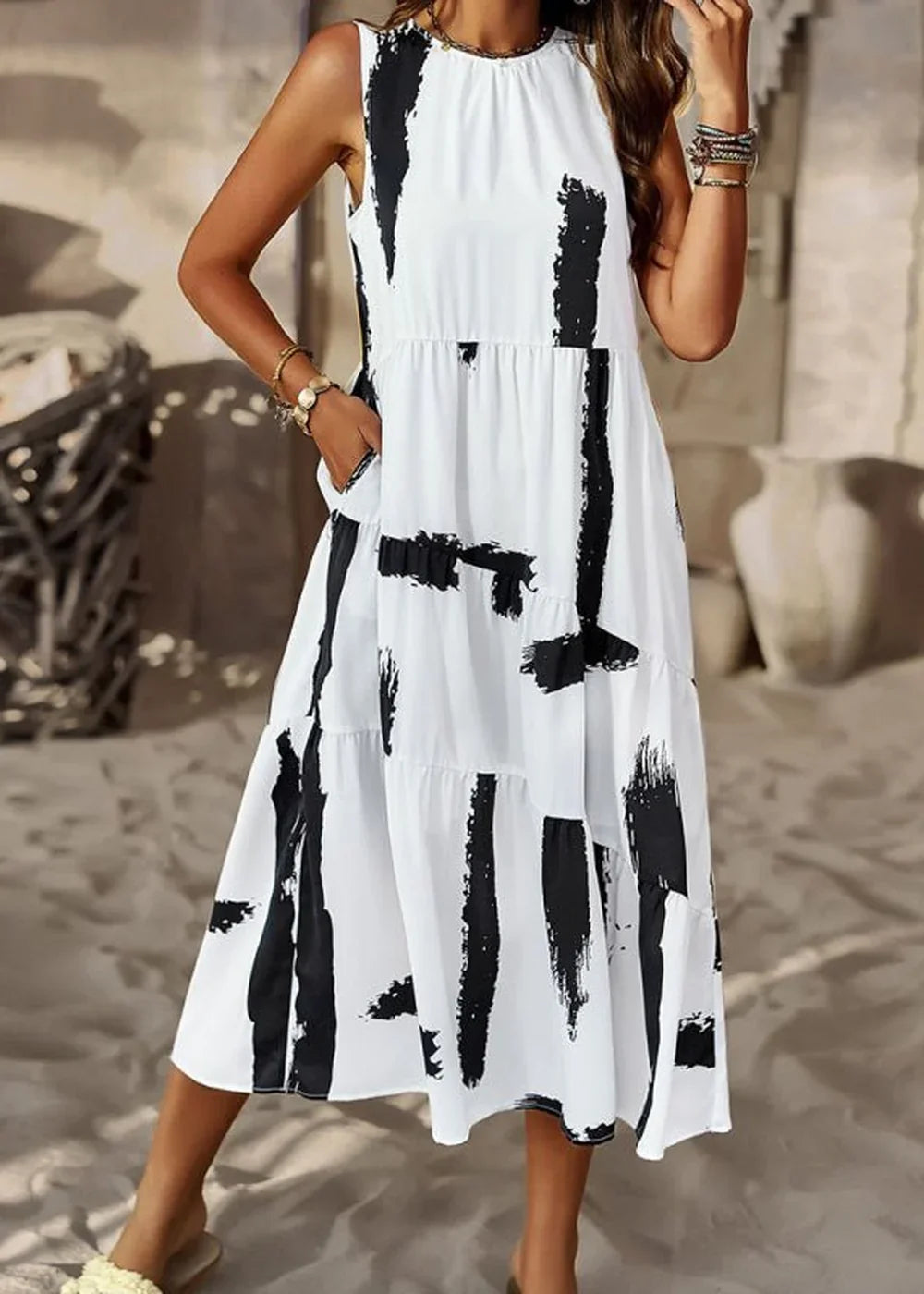 White sleeveless midi dress with black abstract brushstroke print and tiered skirt.