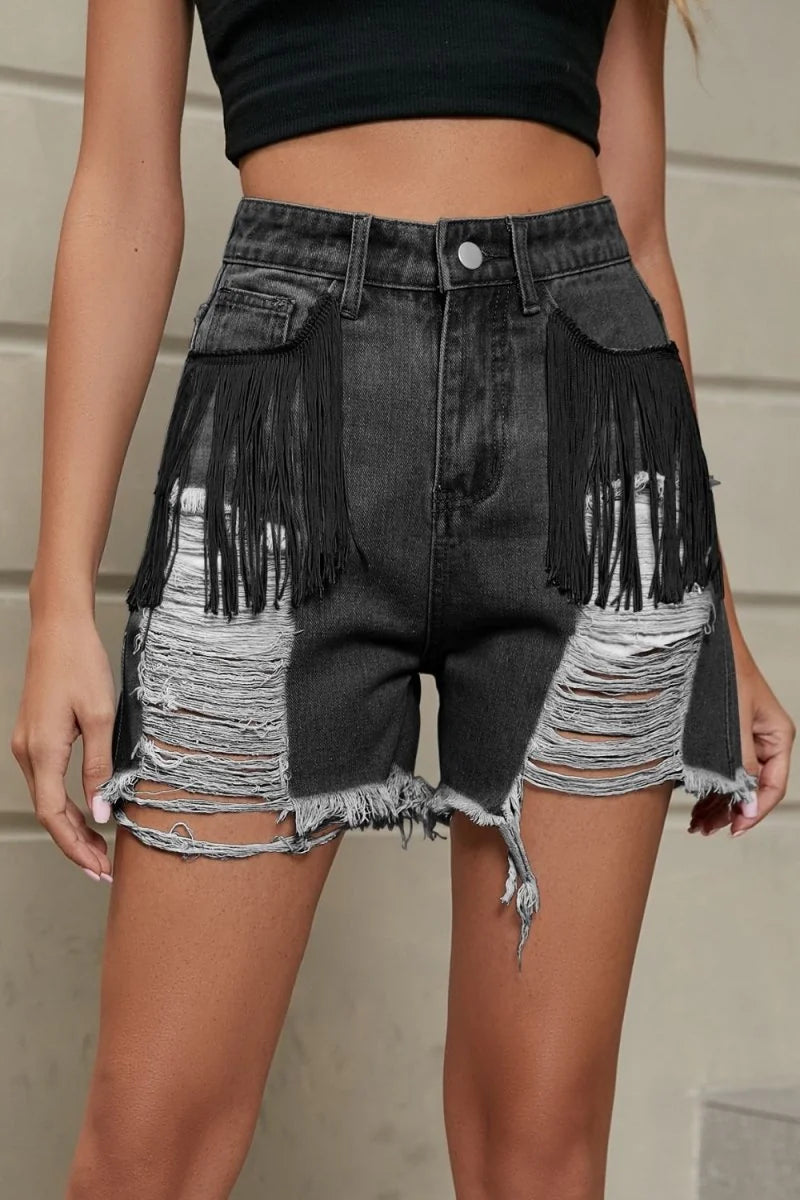 Distressed black denim shorts with fringe detail and ripped legs on model