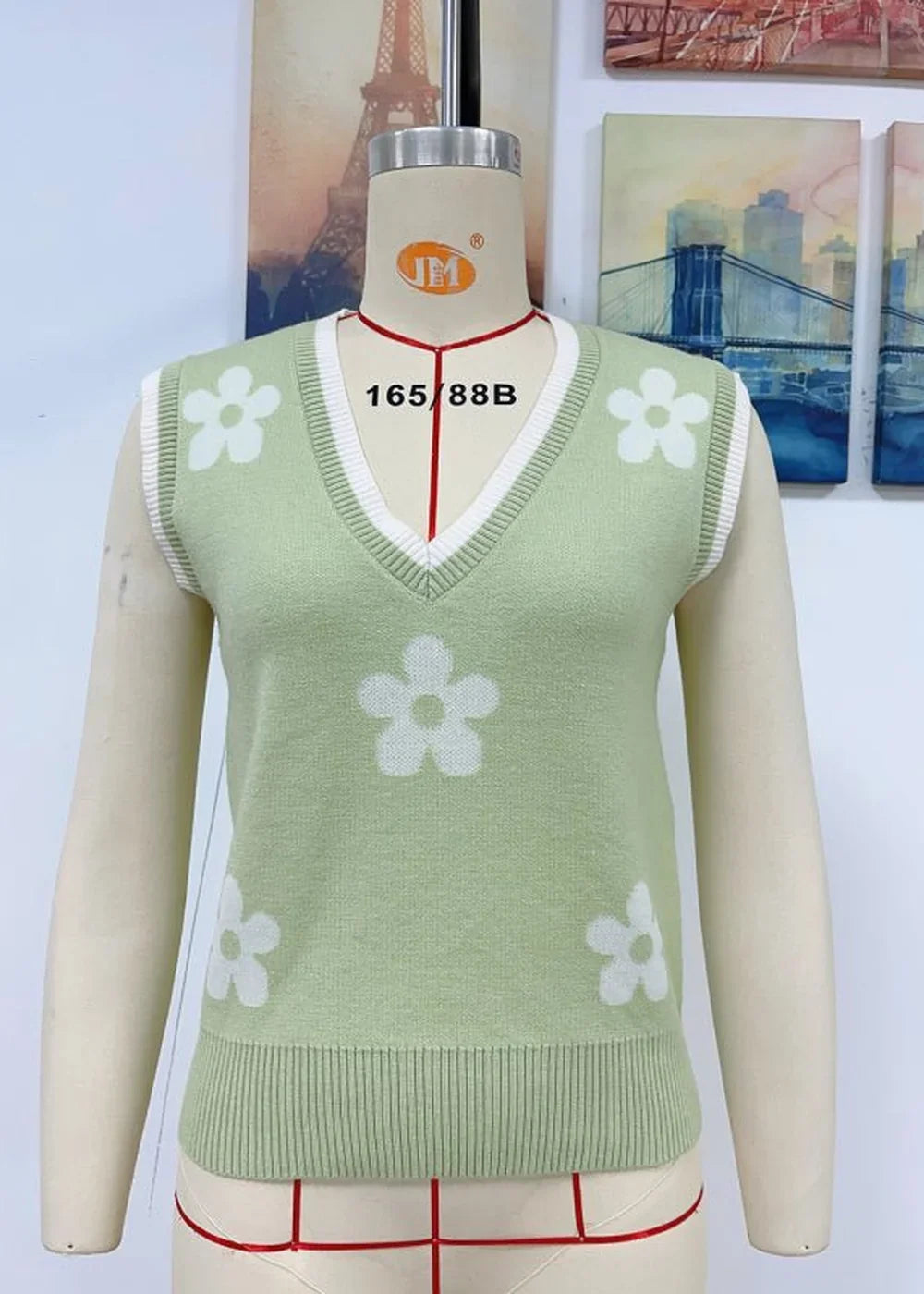 Light green V-neck sweater vest with a white floral pattern and ribbed trim.