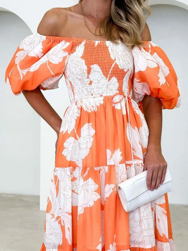 Off-the-shoulder orange dress with white floral print, smocked bodice, and puffed sleeves.