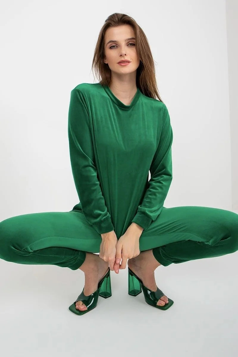 Emerald green velvet tracksuit with clear block heels on model.