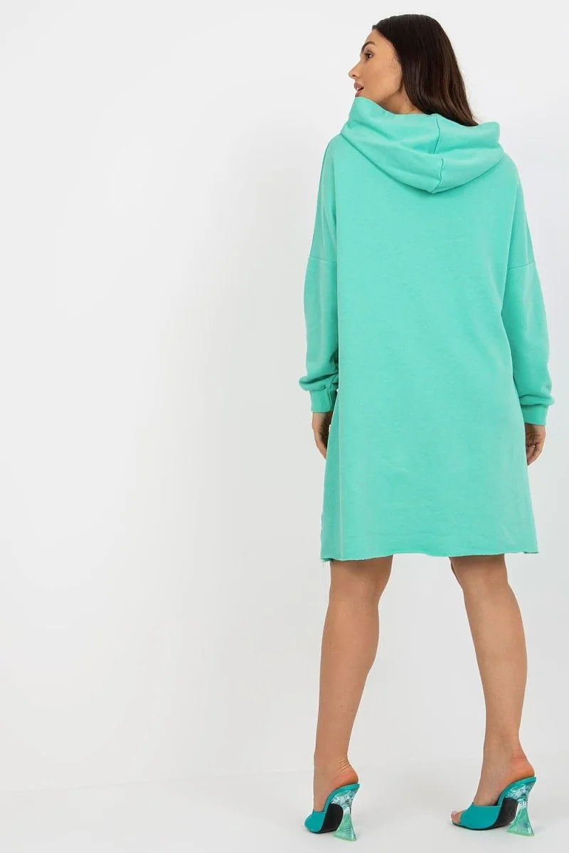 Mint green hooded dress with frayed hem and clear heeled mules on model, back view.
