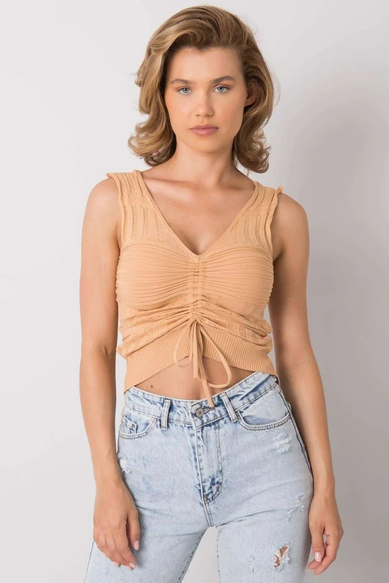 Light peach knit tank top with ruched V-neck and tie, paired with distressed light wash denim jeans.