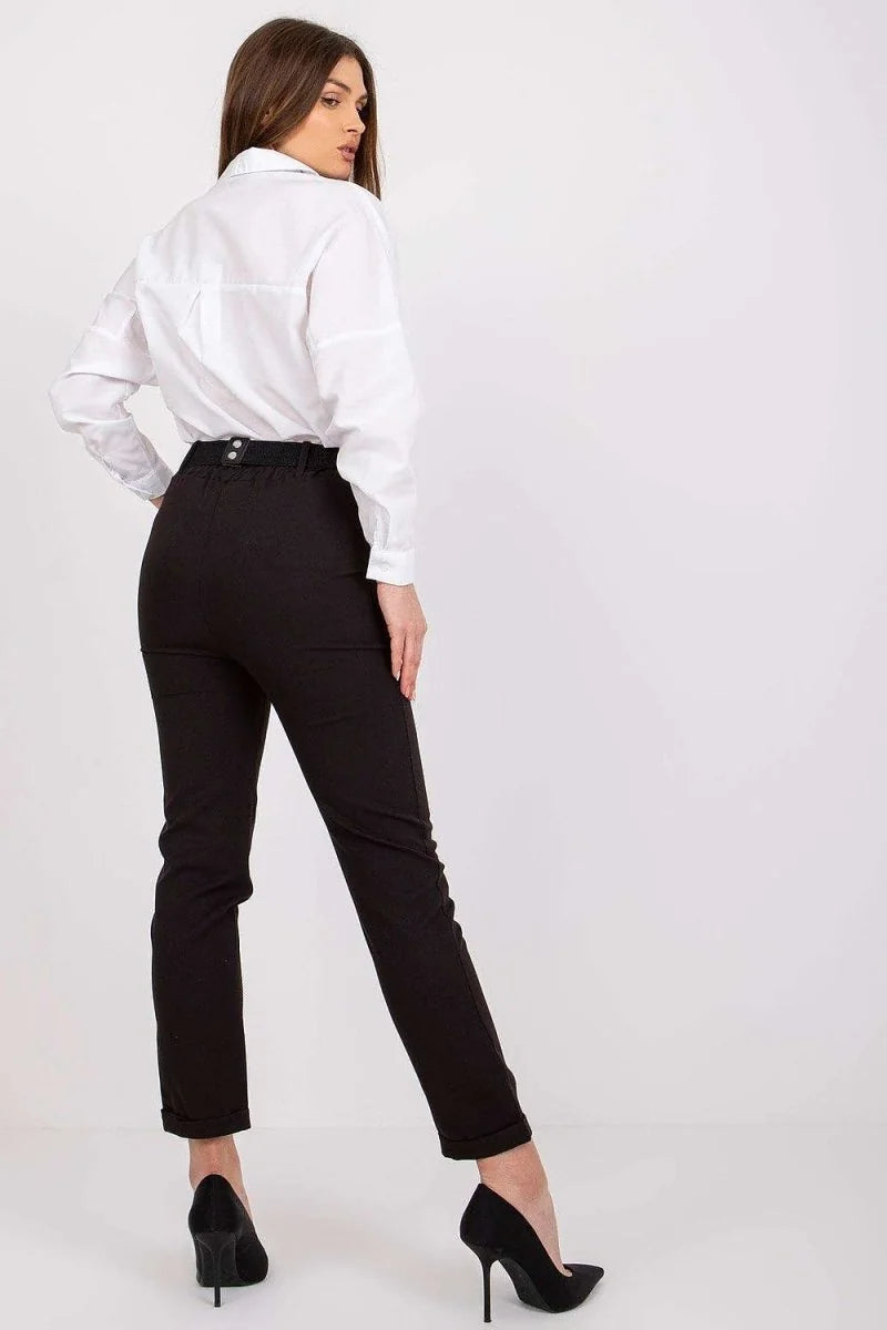 Black high-waisted trousers with a belt and a white collared shirt on a model, viewed from the back.
