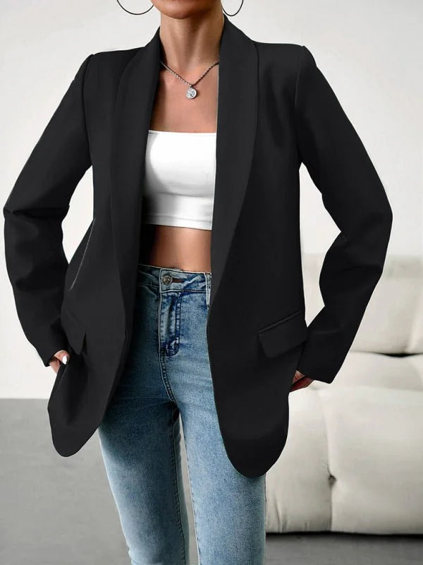 Black blazer with a notched collar and flap pockets, worn over a white crop top and blue jeans.