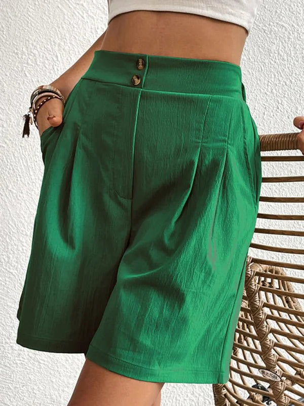 Emerald green pleated shorts with a textured fabric and two-button closure at the waist.