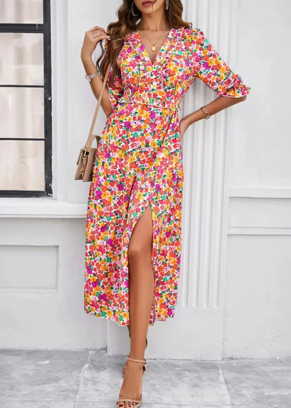 A vibrant floral print midi dress with a V-neck, ruffled details, and a high slit, worn by a model.