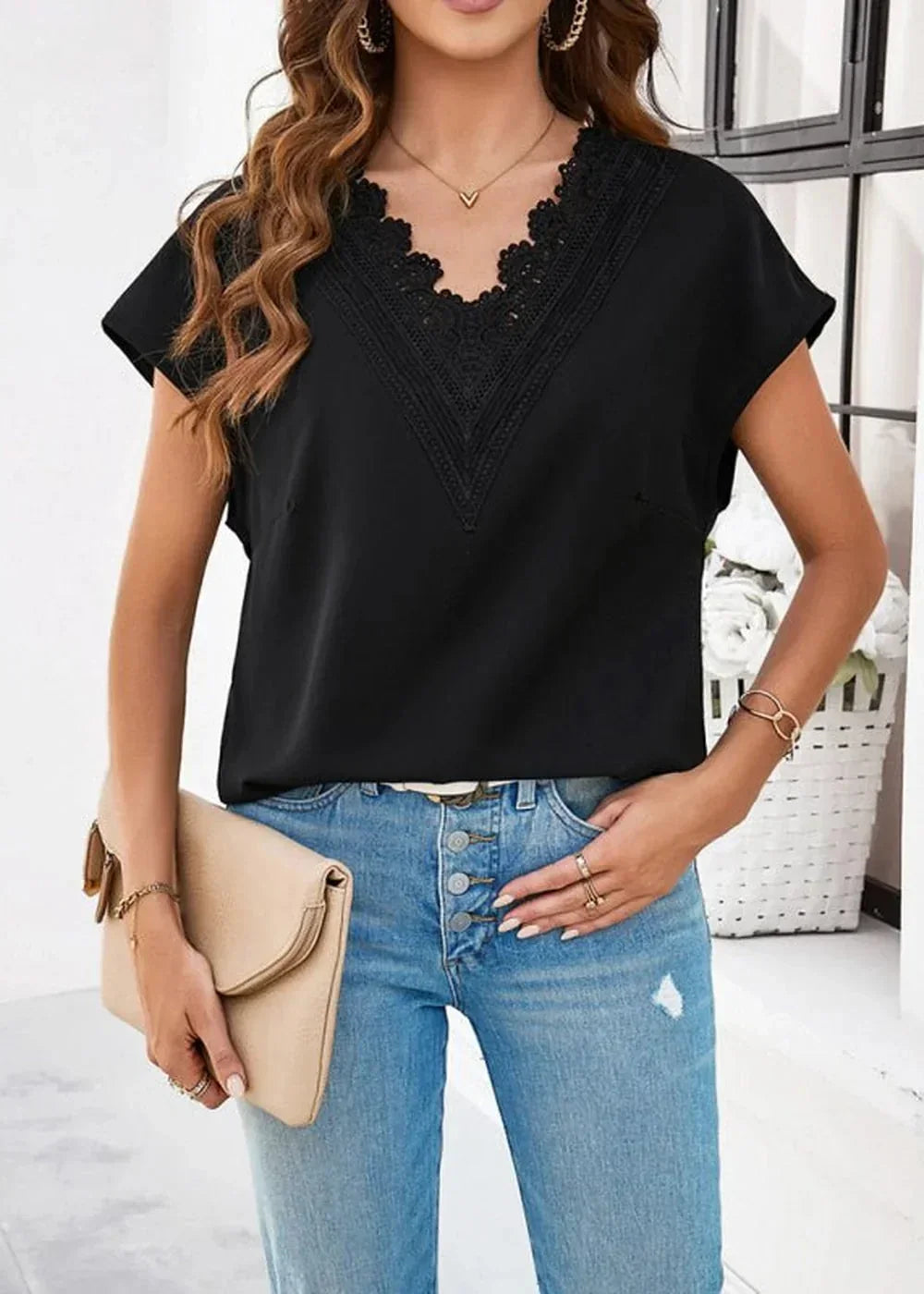 Black lace-trimmed v-neck top with cap sleeves, paired with light wash distressed denim jeans.