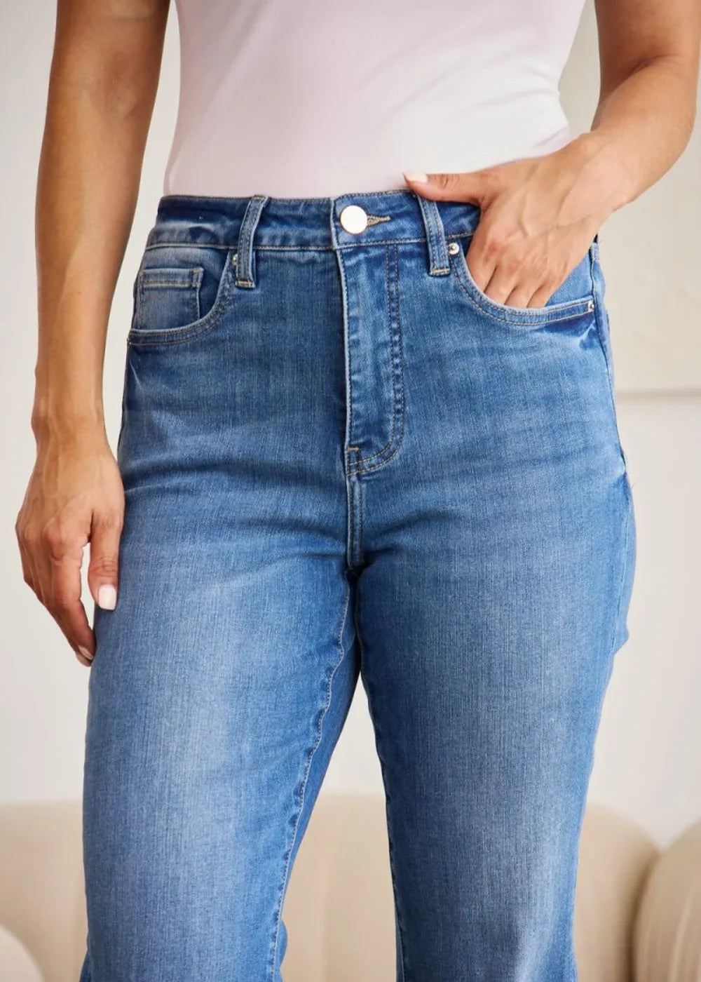 Close-up of medium wash denim jeans with a button closure and pocket detail.