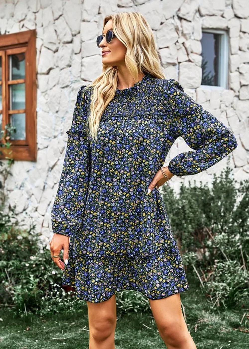 Woman in a navy floral print dress with a smocked bodice and ruffled hem, wearing sunglasses.