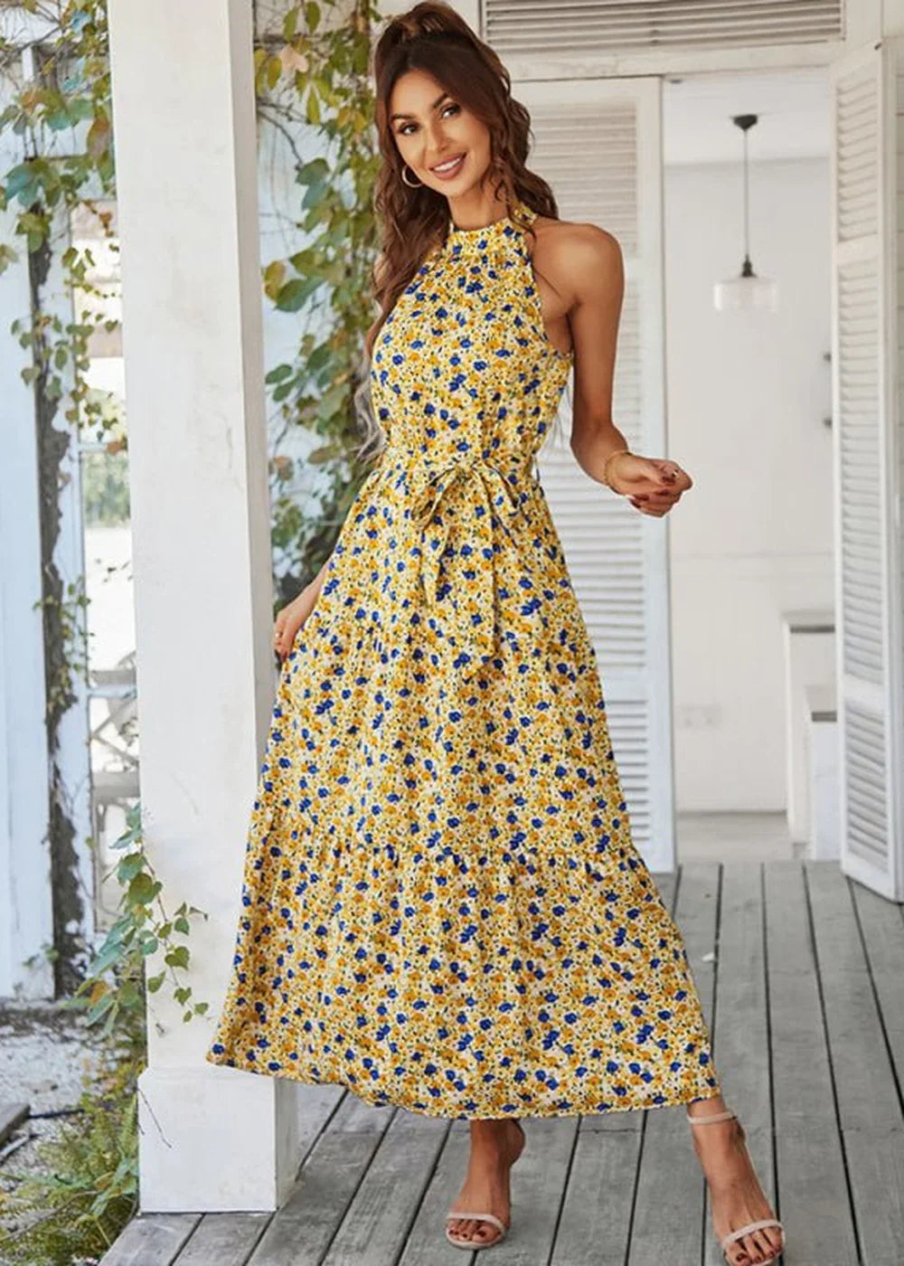 Yellow halter maxi dress with blue floral print and tie waist, on model.