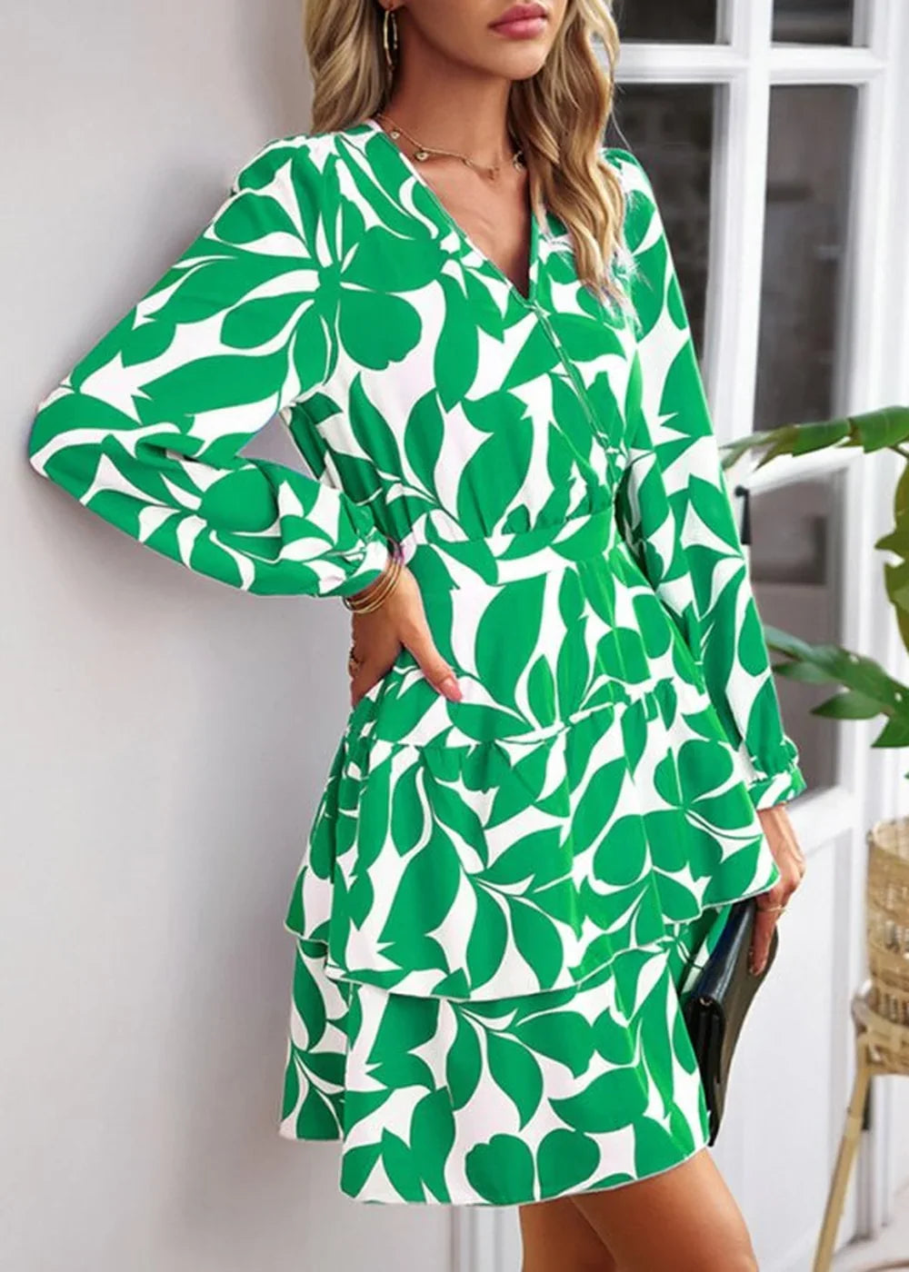 Green and white leaf print mini dress with V-neck and tiered skirt, worn by a model.