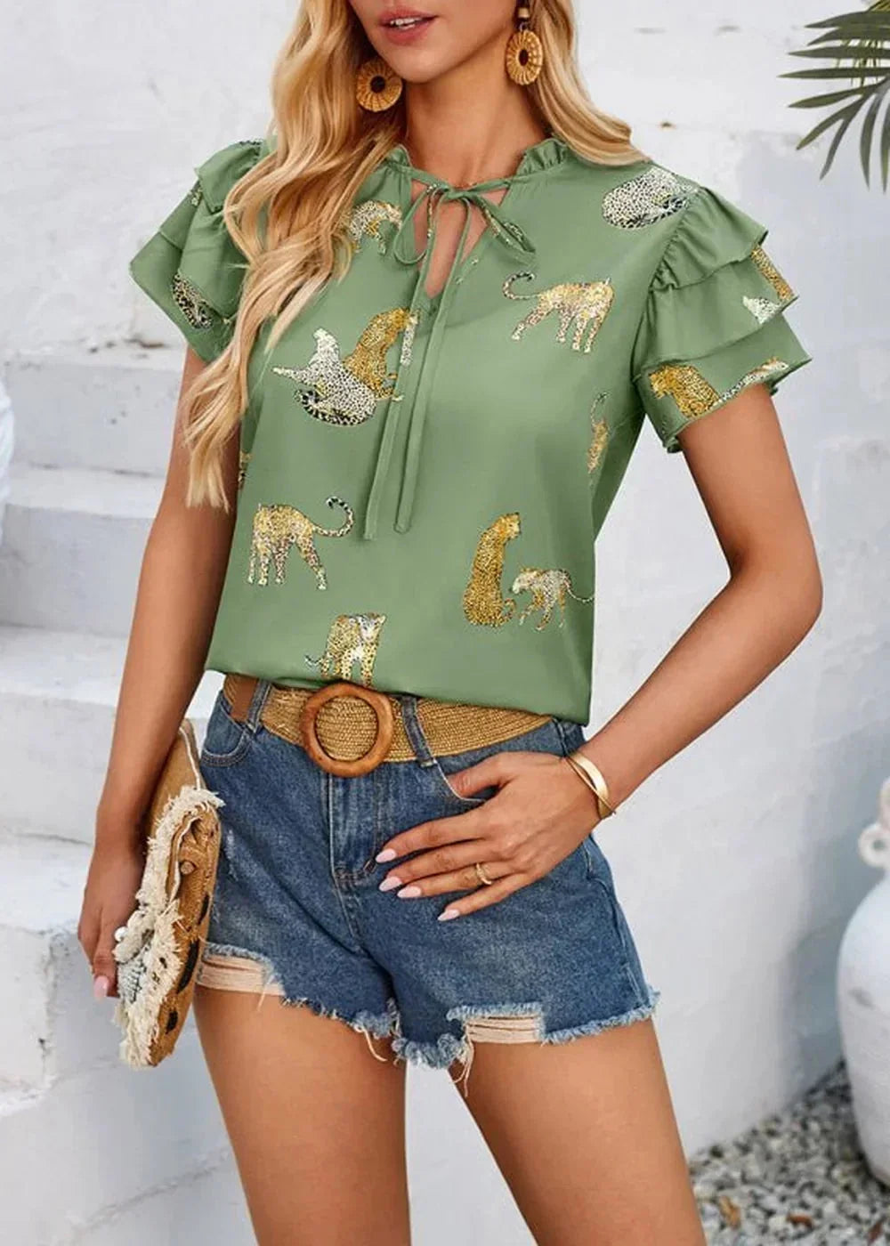 Green blouse with a leopard print, ruffled sleeves, and tie-neck detail, worn by a model.