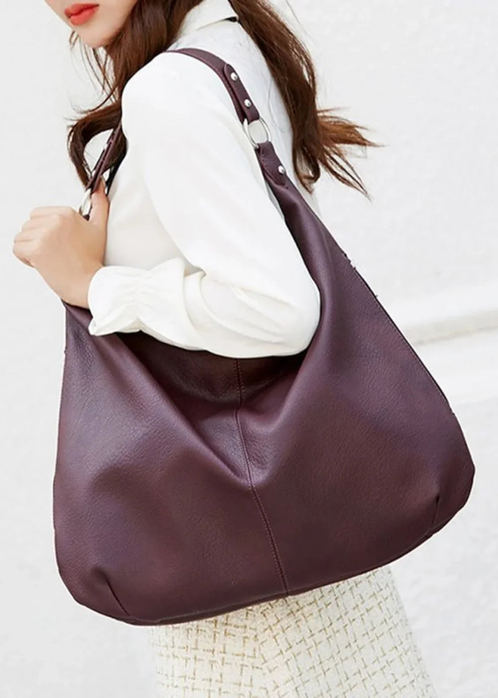 Deep plum PU leather slouchy tote bag with silver ring details, worn on a model.
