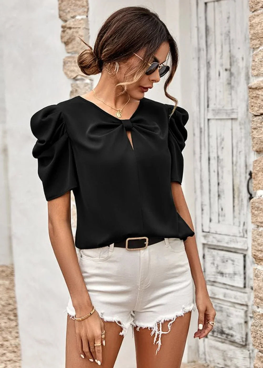 Black puff-sleeve top with bow detail and white distressed shorts on a model.