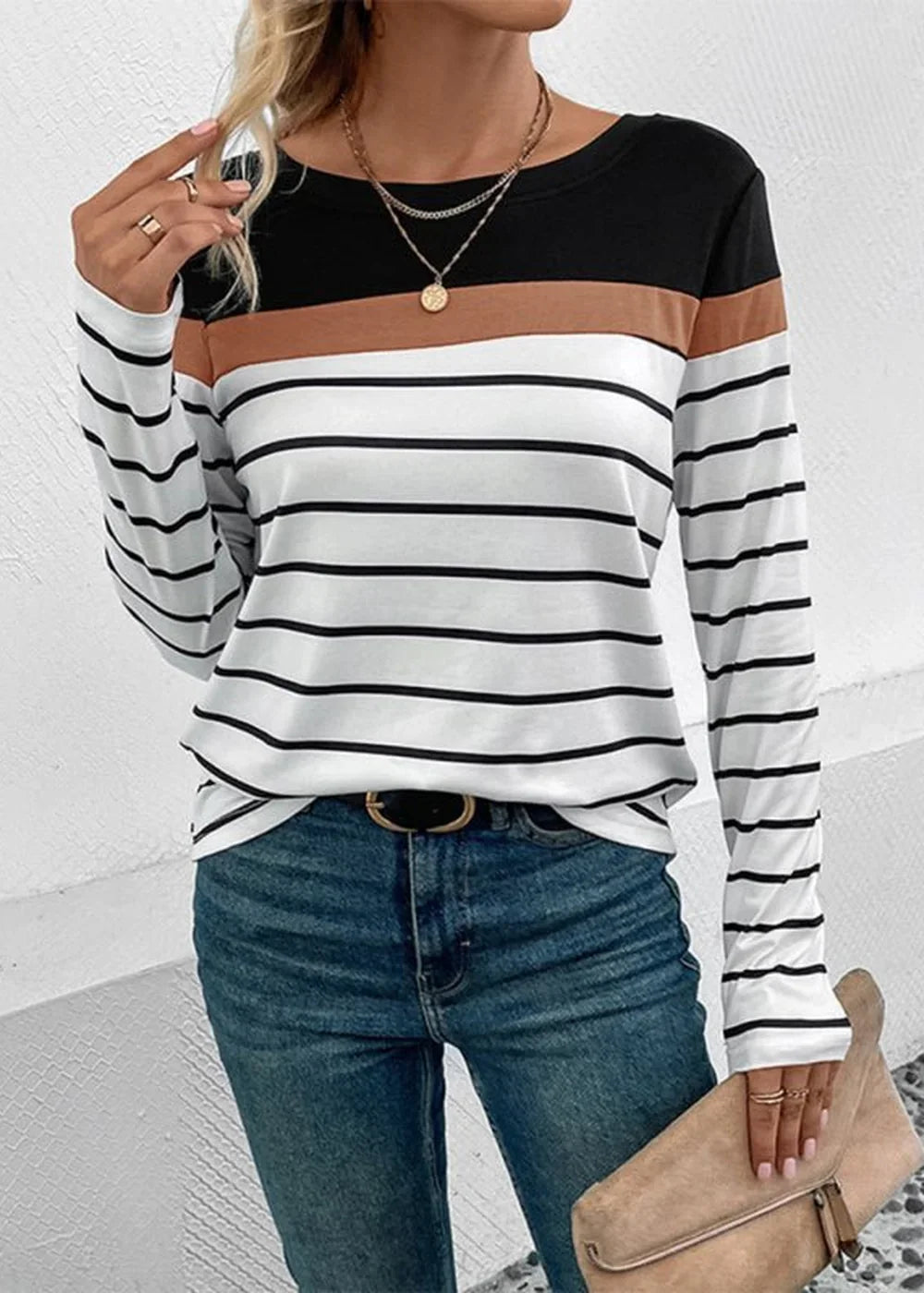 Long-sleeve striped top with black, brown, and white bands, paired with blue jeans and gold jewelry.