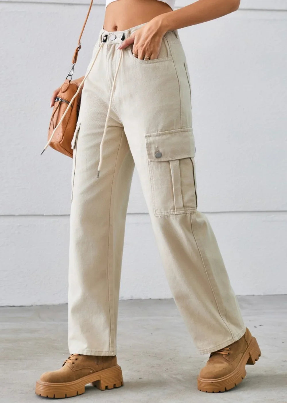 Cream colored cargo pants with drawstring waist and chunky brown boots on model