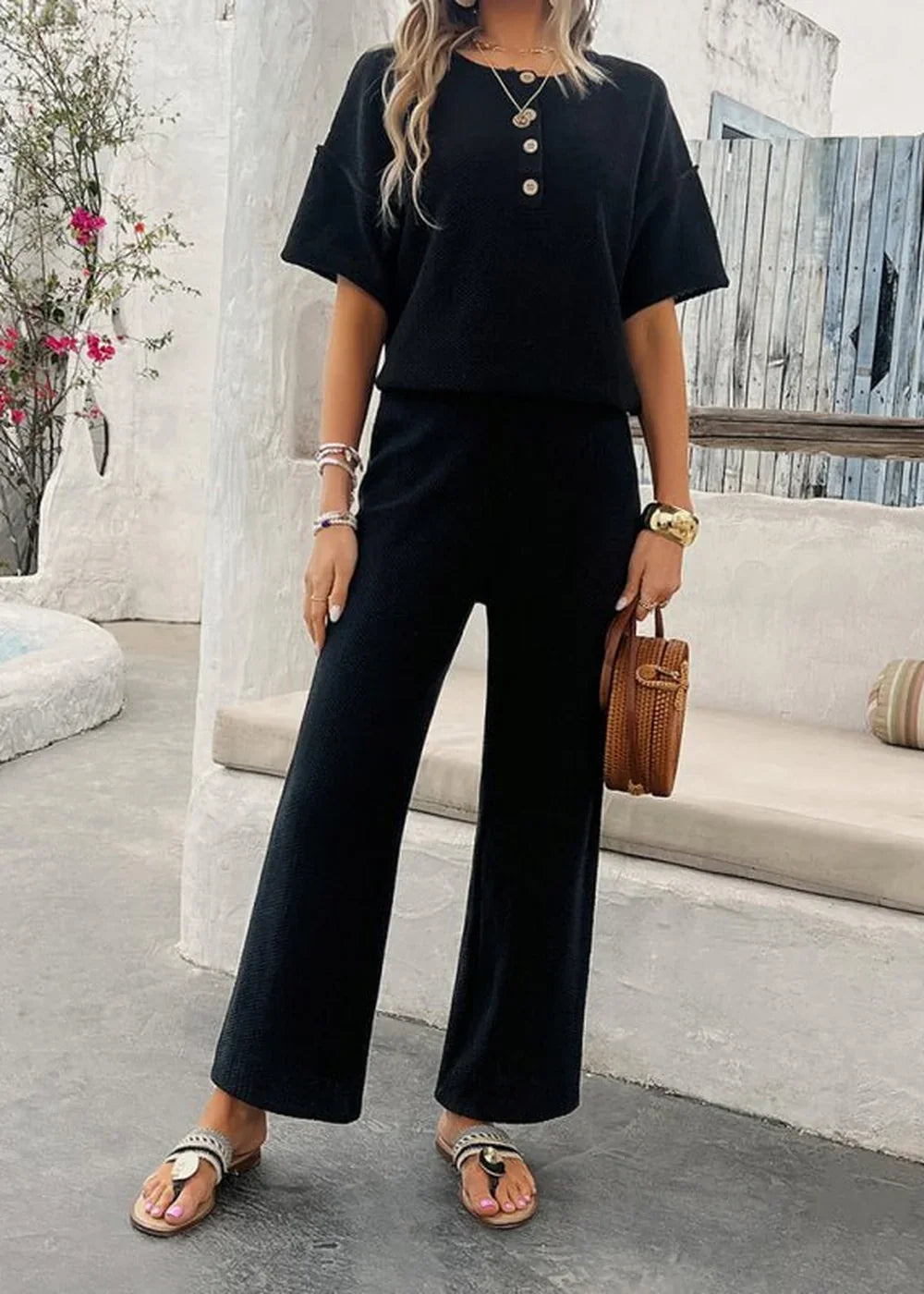 Black ribbed knit short-sleeve top and wide-leg pants set with gold-button detail, on model.