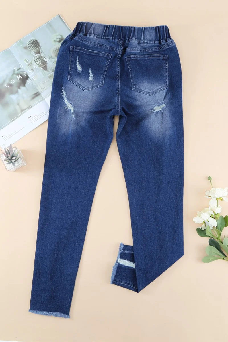 Dark wash distressed denim jeans with frayed hem and elastic waistband.