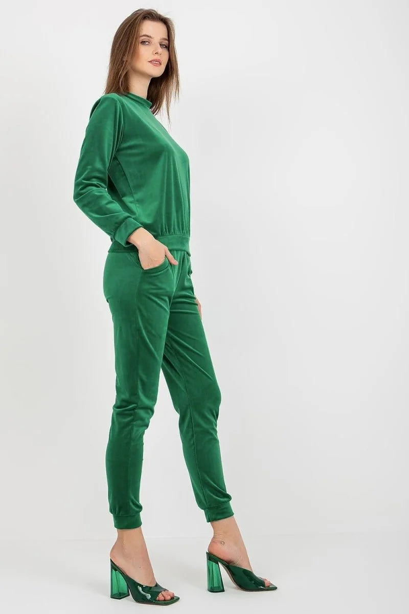 Emerald green velvet pants with pockets, on a model wearing clear heels.