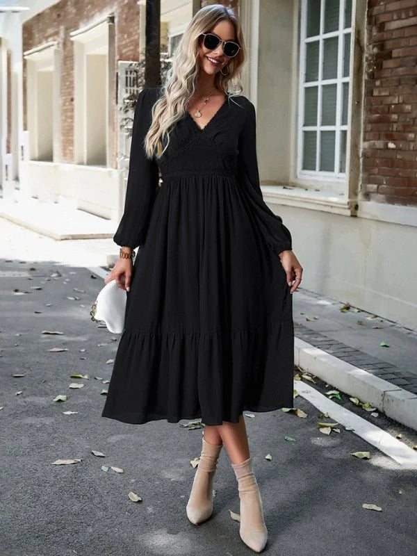 Black long-sleeve tiered midi dress with a V-neck and smocked bodice, worn by a model on an outdoor street.