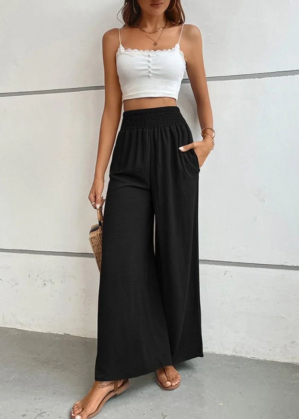 Black wide-leg pants with smocked waist and textured fabric, on model.