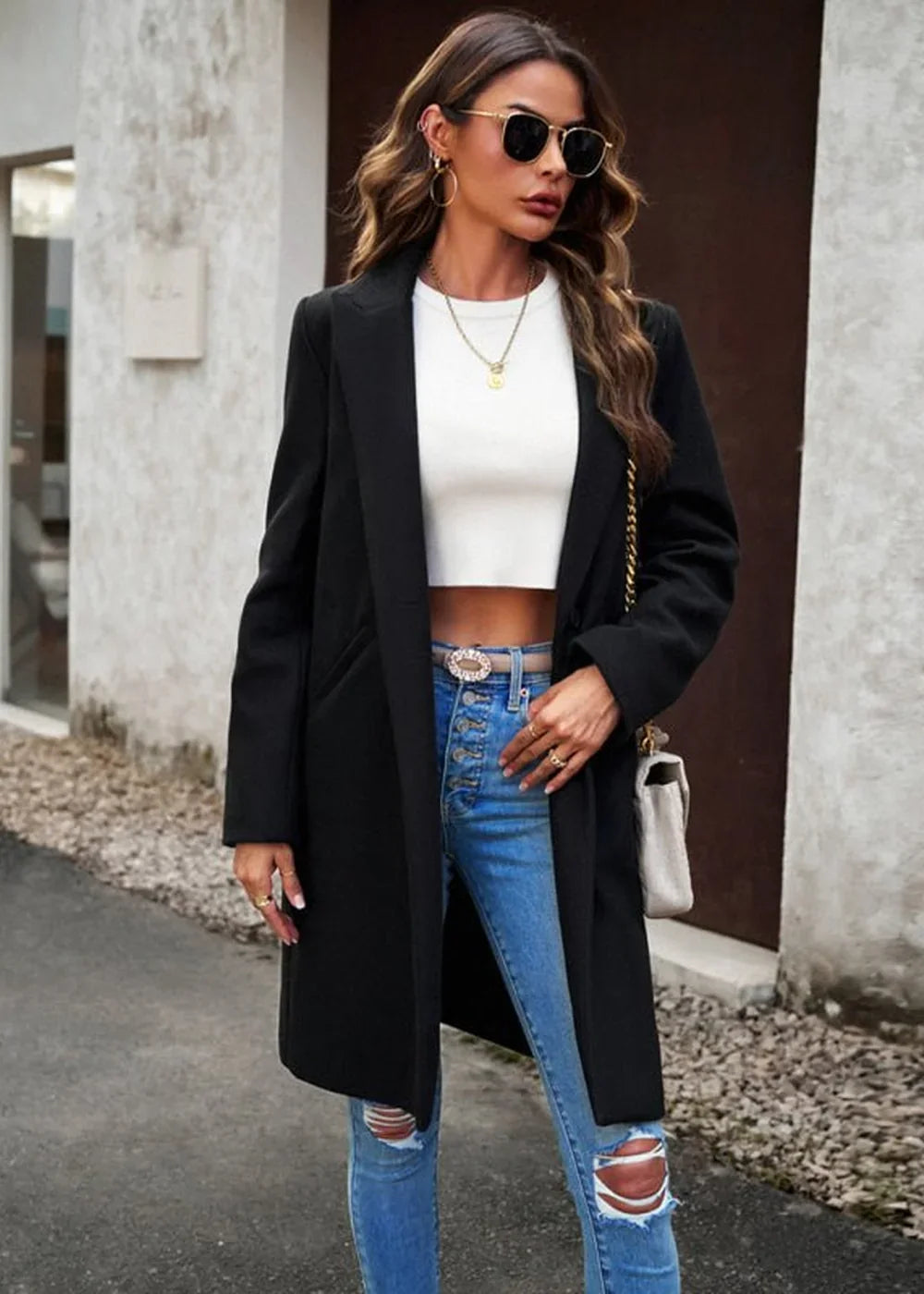 Black polyester trench coat on a woman wearing ripped jeans and a white crop top.